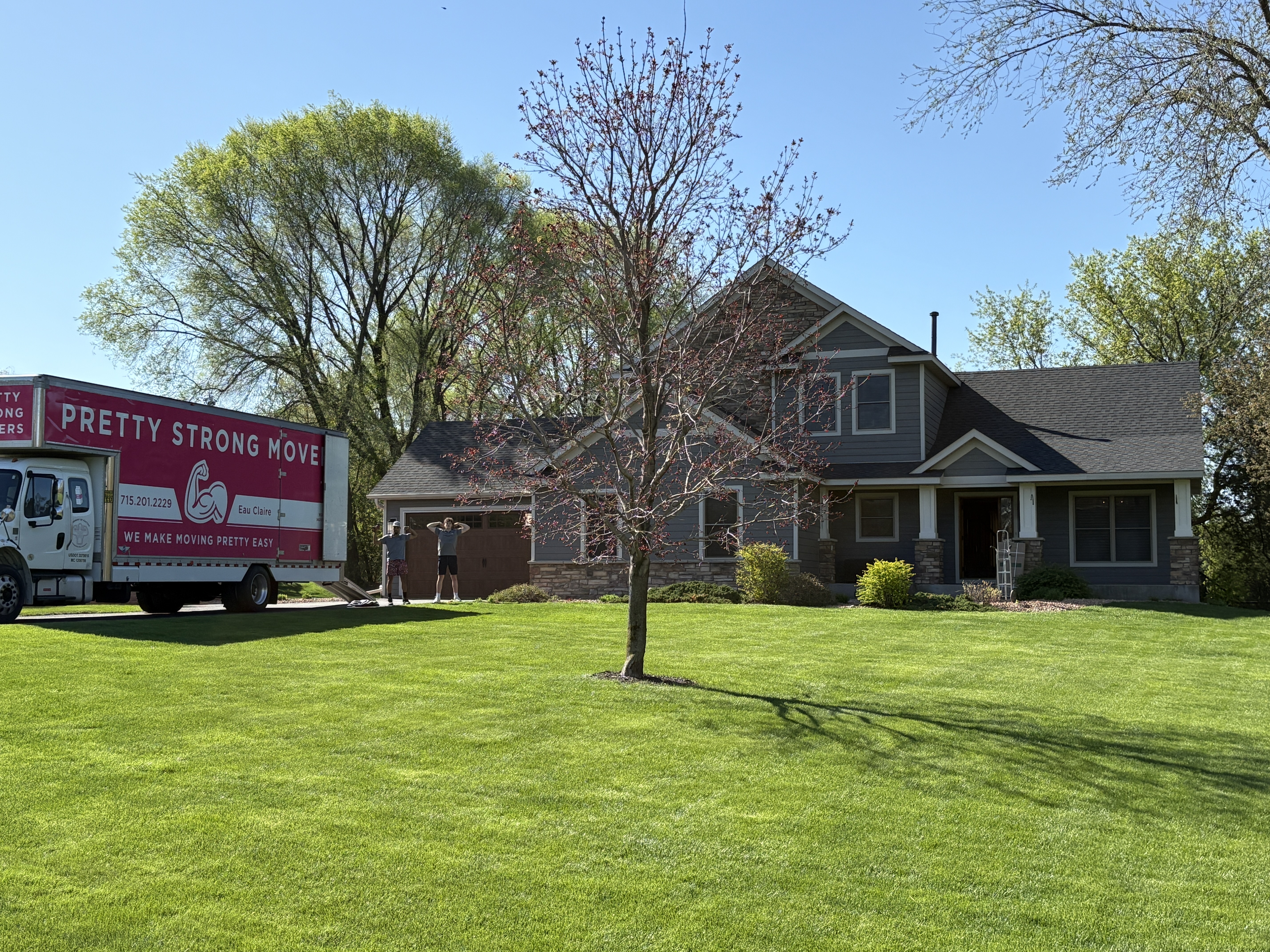 Pretty Strong Movers flexing in front of a house